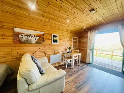 a living room with a white couch and a wooden wall at Hwyl in Abbey-Cwmhir