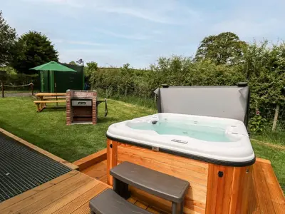 a bath tub sitting on a deck with a picnic table at Hwyl in Abbey-Cwmhir