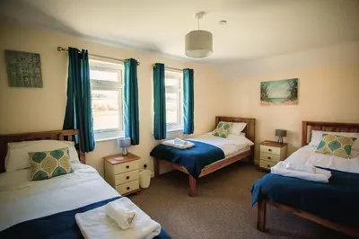 a bedroom with two beds and blue curtains at Lower Pentre in Llanddewi Ystradenny