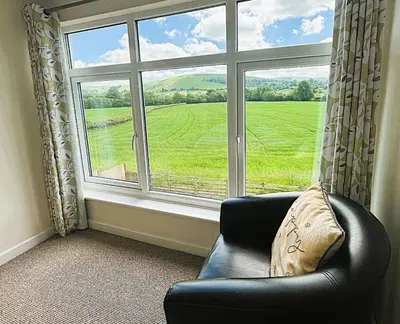 a black leather chair sitting in front of a large window at Lower Pentre in Llanddewi Ystradenny