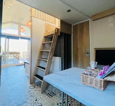 a loft bed in a room with a table at Meadow Retreat in Rhayader
