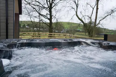 a hot tub filled with water next to a house at Oak Tree View in Nantmel