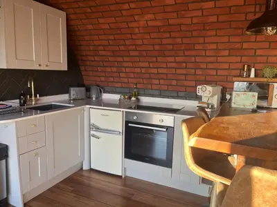 a kitchen with white cabinets and a brick wall at Otters View in Rhayader