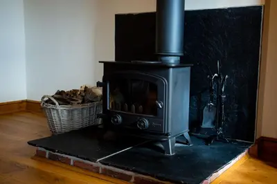 a black stove in a room with a basket at Pentre Fawr in Llanddewi Ystradenny