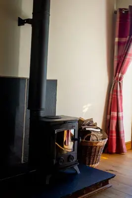 a black stove with a basket in a room at Pentre Fach in Llanddewi Ystradenny