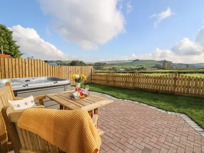 a patio with a table and chairs and a fence at Tegfan Barn in Pant-y-dwr