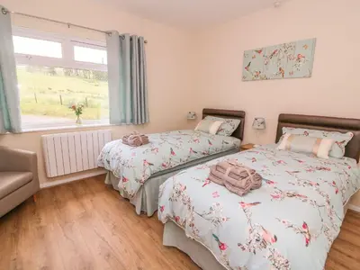 a bedroom with two beds and a window at Tegfan Bungalow in Pant-y-dwr