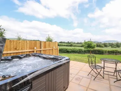 a hot tub on a patio with a table and chairs at Tegfan Bungalow in Pant-y-dwr