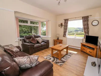 a living room with a leather couch and a television at Tegfan Bungalow in Pant-y-dwr