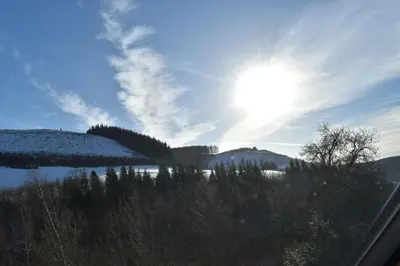 a view of a snow covered mountain with the sun in the sky at The Hayloft in Knighton