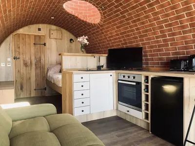 a kitchen with a couch and a brick wall at Mountain View in Llanfair Caereinion