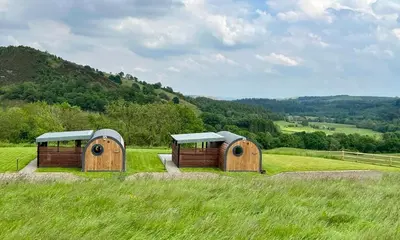 two hobbit houses in a field of grass at Yr Onnen in Oswestry