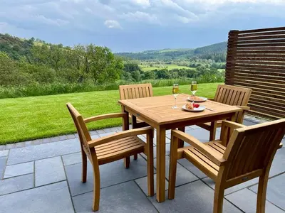 a wooden table with two chairs and two glasses of wine at Yr Onnen in Oswestry