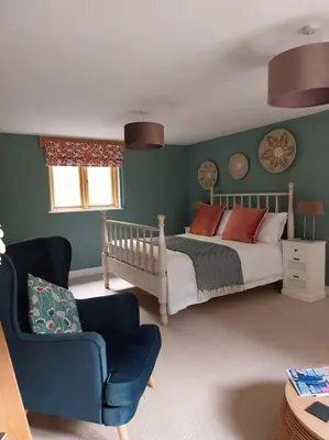 a bedroom with a bed and a chair at The Hen Den in Ludlow