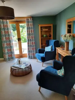 a living room with blue chairs and a table at The Hen Den in Ludlow