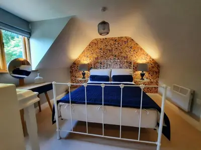 a bedroom with a white bed with a blue comforter at The Hen Den in Ludlow