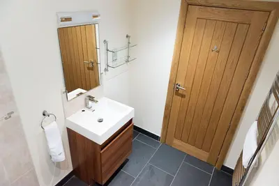 a bathroom with a sink and a wooden door at Yr Hen Beudy in Aberystwyth