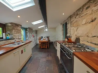 a kitchen with a stove and a stone wall at Y Cwtch - Panoramic mountain views within Snowdonia's National Park - 4x4 only in Dolgellau