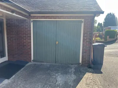 a green garage door on a brick house at Twyngaer, a spacious 3 bedroom bungalow sleeps 5 in Knighton