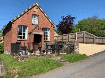 an old red brick house with a fence at St Milburga Chapel in Stoke Saint Milborough