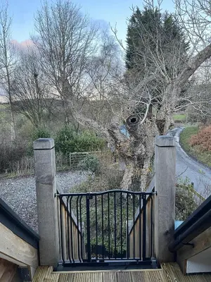 a wooden walkway with a gate in front of a tree at Upper Gelli Luxury Holiday Lodge, Converted Dairy & Cosy Shepherds Huts in Welshpool