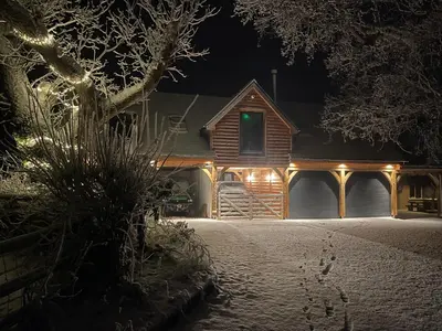 a house covered in snow at night with lights at Upper Gelli Luxury Holiday Lodge, Converted Dairy & Cosy Shepherds Huts in Welshpool
