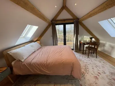 a bedroom with a bed and a table and windows at Upper Gelli Luxury Holiday Lodge, Converted Dairy & Cosy Shepherds Huts in Welshpool