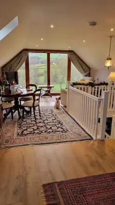a dog sitting in the middle of a living room with a table at Delightful Country Cottage in a lovely rural area in Ludlow