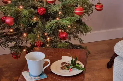 a table with a cup and a plate of food and a christmas tree at Delightful Country Cottage in a lovely rural area in Ludlow