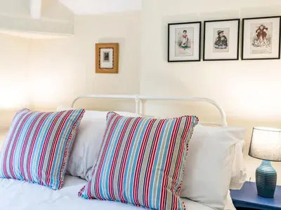 a bedroom with a white bed with striped pillows at Cosy 2 bedroom Victorian Cottage - Pass the Keys in Ludlow
