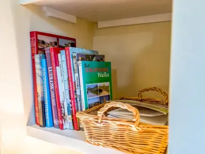 a book shelf with books and a basket on it at Cosy 2 bedroom Victorian Cottage - Pass the Keys in Ludlow