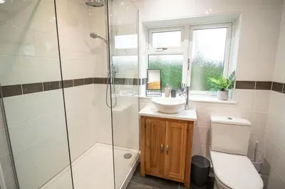 a bathroom with a shower and a toilet and a sink at Ger Yr Afon in Saint Harmon