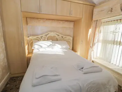 a bedroom with a white bed with two towels on it at Bryn Berthen in Penrhyndeudreath