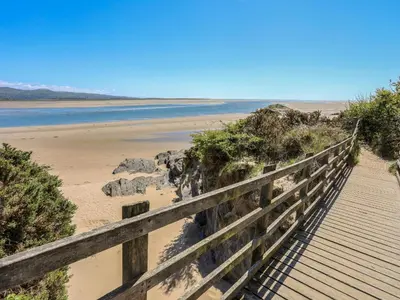 a wooden boardwalk leading to a beach with the ocean at Bryn Berthen in Penrhyndeudreath
