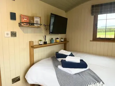 a room with a bed with blue and white towels at Poppy in Rhayader