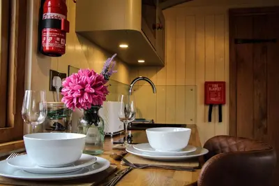 a table with plates and bowls and a vase of flowers at Poppy in Rhayader