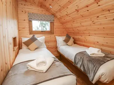 two beds in a log cabin with a window at Primrose in Rhayader