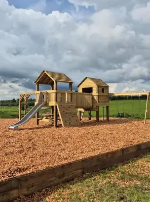 a wooden playground with a slide in a field at Snowdrop in Rhayader