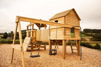 a wooden play house with a swing at Tulip in Rhayader