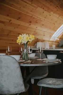 a table with chairs and a vase of yellow flowers at Daisy in Rhayader
