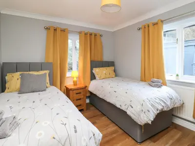 two beds in a bedroom with yellow curtains at Pen Y Banc in Builth Wells