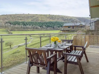 a wooden table and chairs on a deck with a view at Red Kite Lodge - Uk32610 in Old Radnor