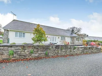 a white house with a stone retaining wall at Craigfryn in Llanerch-Aeron