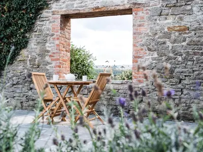 a table and chairs in a garden with flowers at Blackrock Barn in Clifford