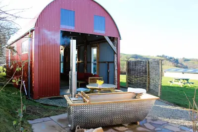 a red shed with a tub in front of it at The Edwardian Caravan 'Dora' in Lampeter