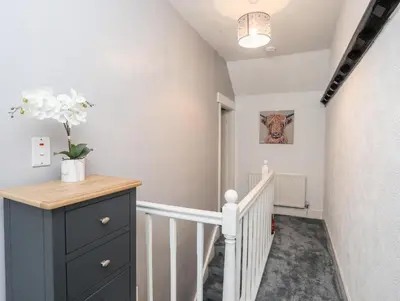 a hallway with a staircase with a blue dresser and a stairway at Llys Mair in Bala