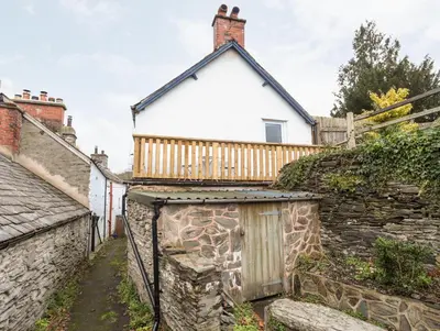 a house with a stone wall and a fence at Llys Mair in Bala