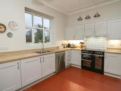 a kitchen with white cabinets and black appliances at Tirallen in Llanwrda