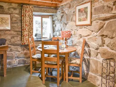 a stone walled dining room with a wooden table and chairs at Hafan Prysor in Trawsfynydd