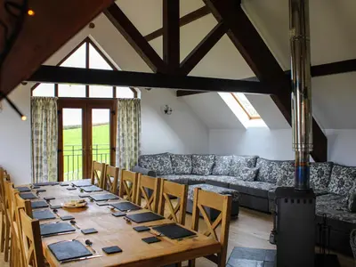 a dining room with a long table and a couch at Bedw Barn in Newtown